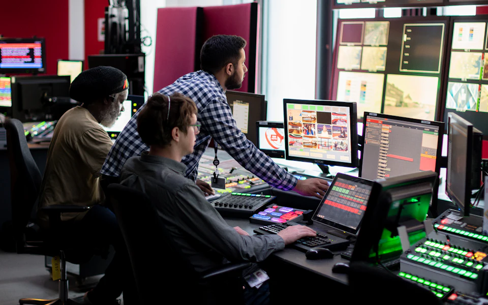 Engineers at a desk with several monitors